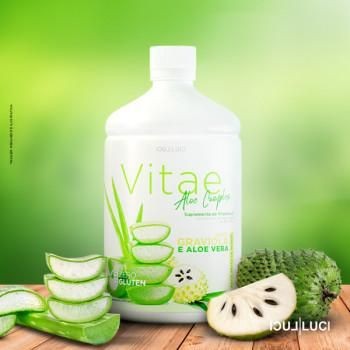 Bottle of Vitae aloe vera drink with sliced aloe and soursop fruit on a wooden surface.
