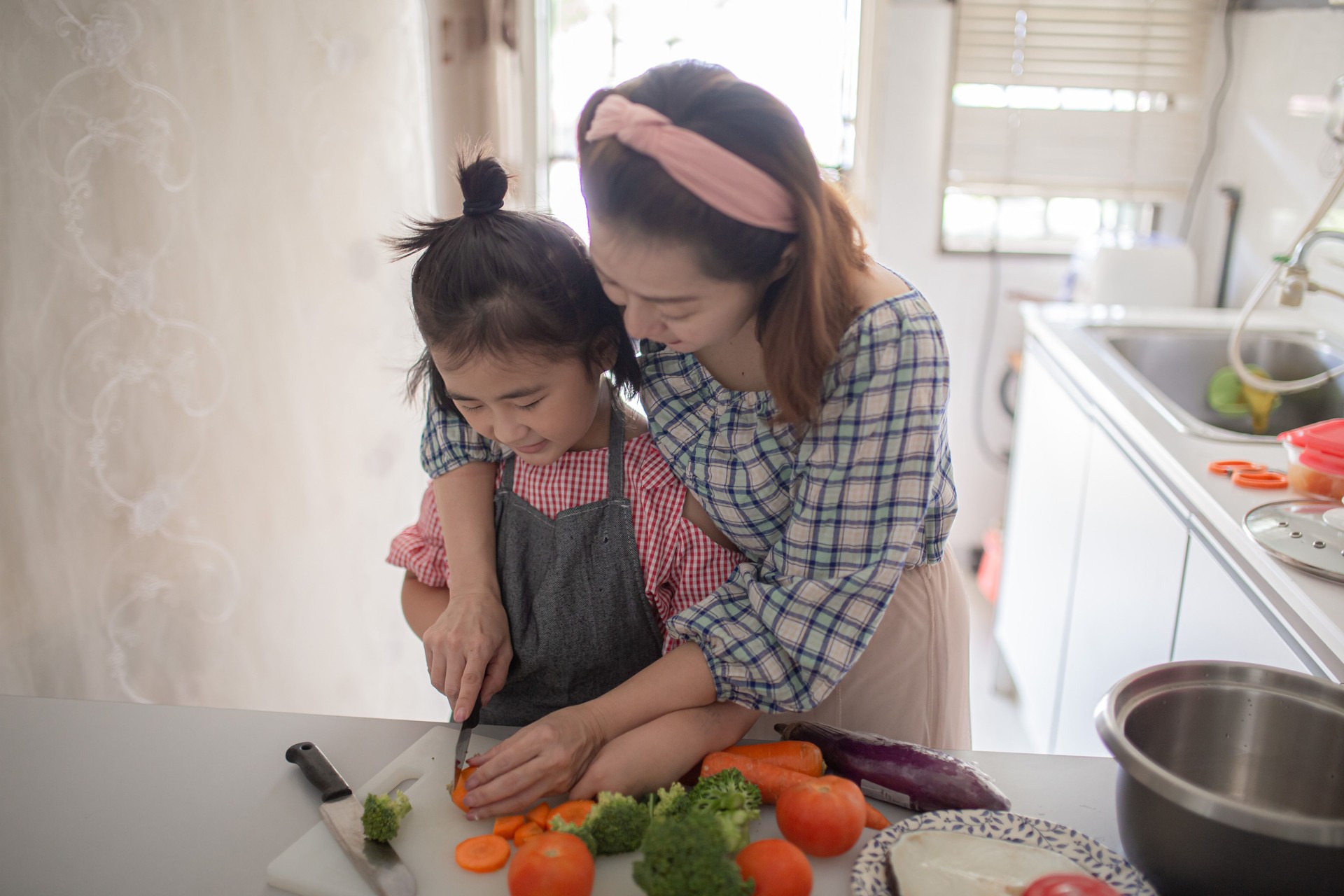 Mãe chinesa asiática preparando comida no balcão da cozinha com sua filha